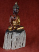 Houten Boeddhabeeld in Bhumisparsha mudra op boomstronk